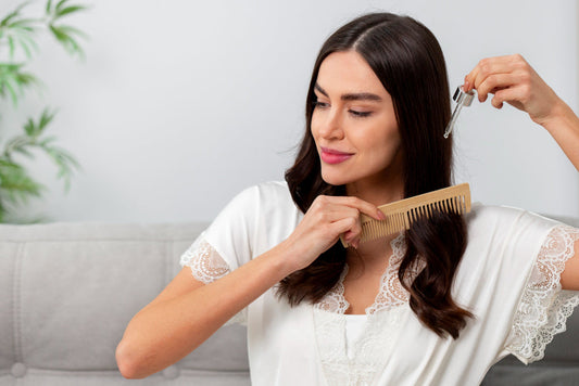Woman applying rosemary Growth Oil with a dropper while combing her hair