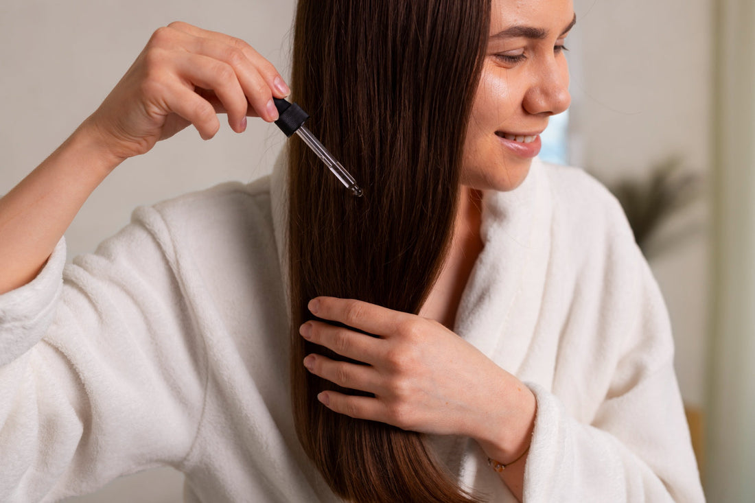 Woman applying Organic Growth Oil serum to the lengths of her hair with a dropper