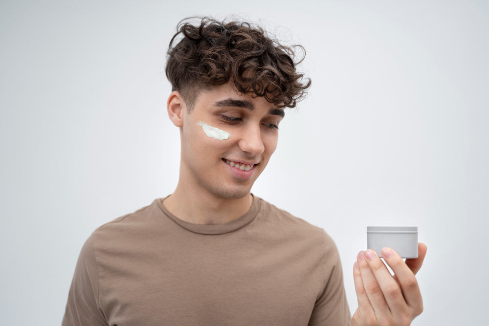 Man with moisturizer swiped on his cheek holding a face cream jar