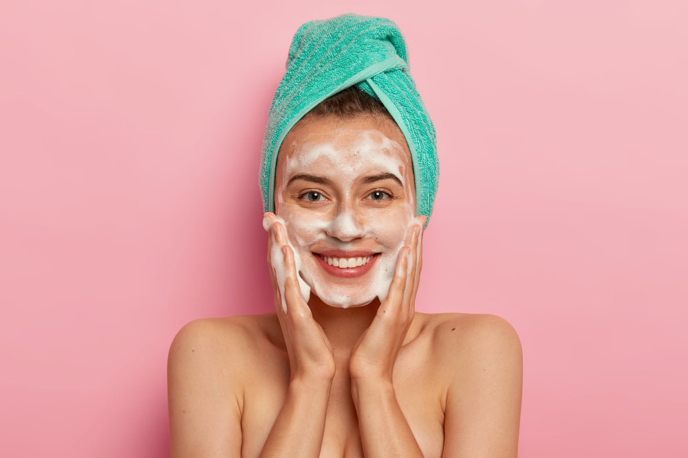 Smiling woman in a hair towel doing a deep cleansing facial at home