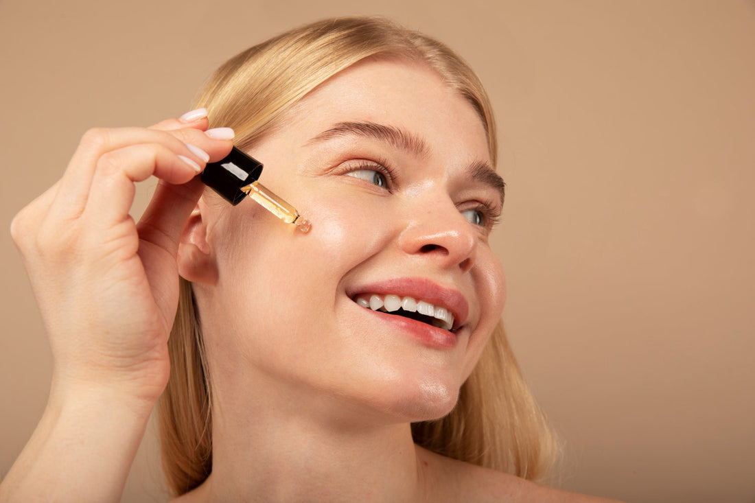 Smiling woman holding a dropper of facial cleansing oil near her cheek