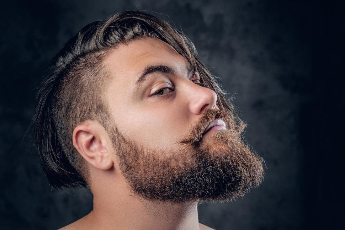 Side profile of a man with a full, healthy beard against a dark background