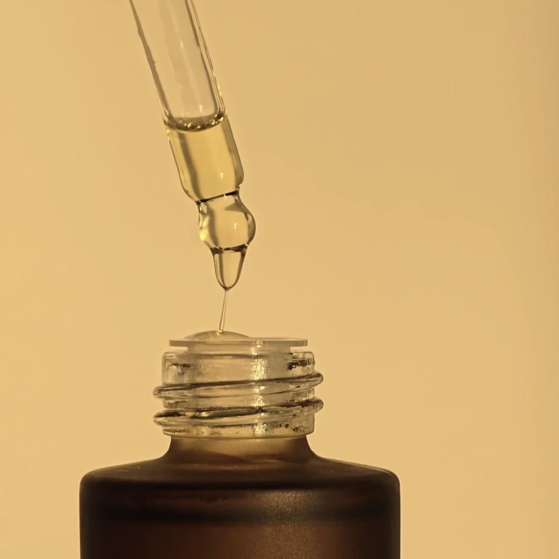 Close-up of a dropper releasing Organic Growth Oil back into its bottle