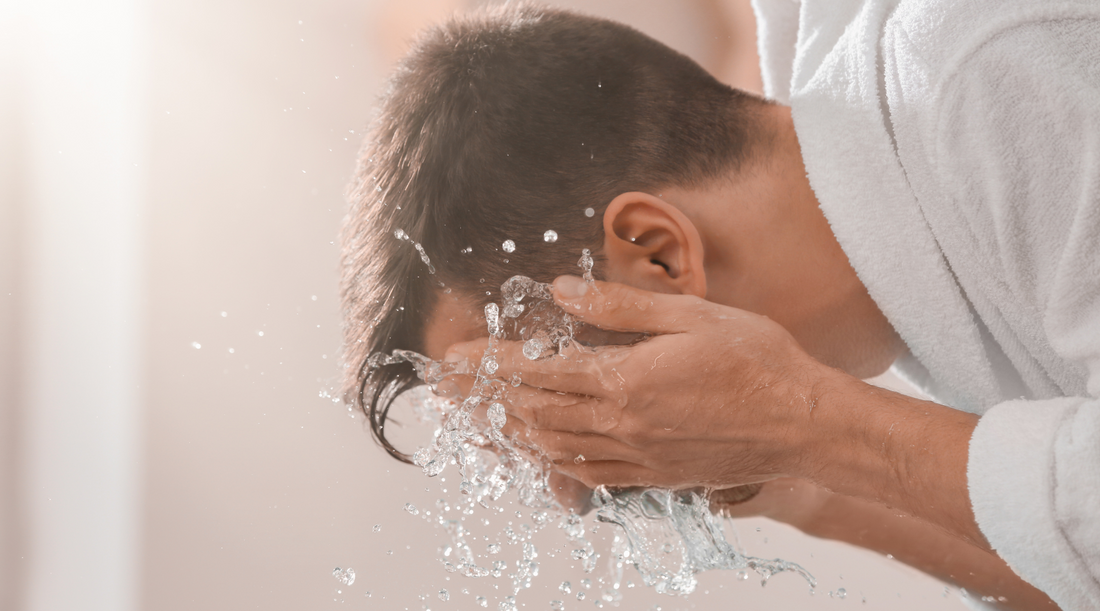 Man splashing water on his face while washing with face wash