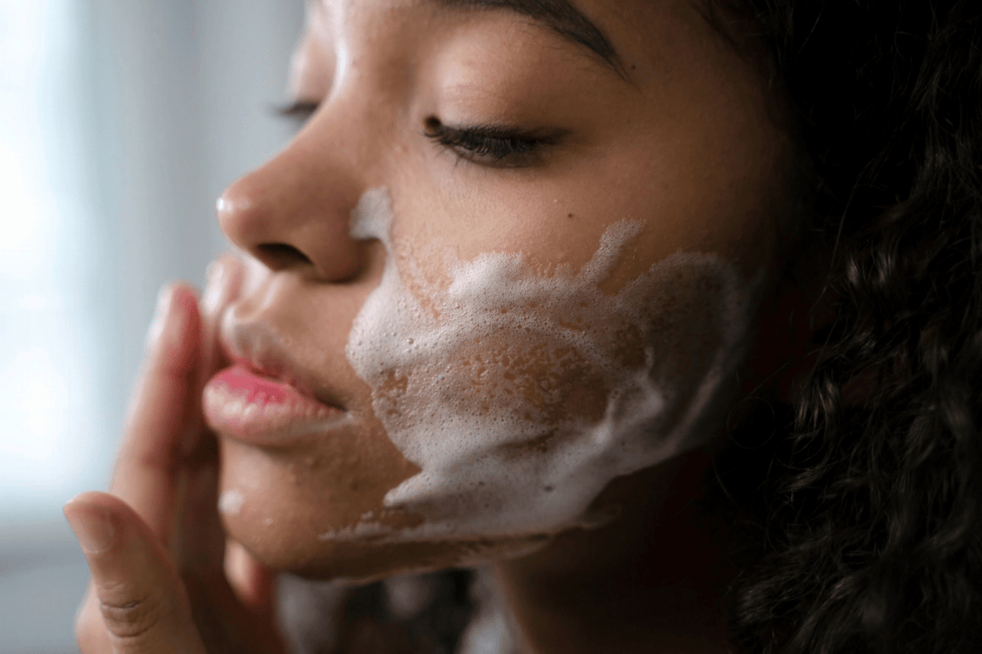 Woman cleansing her face with a sudsy organic cleansing oil