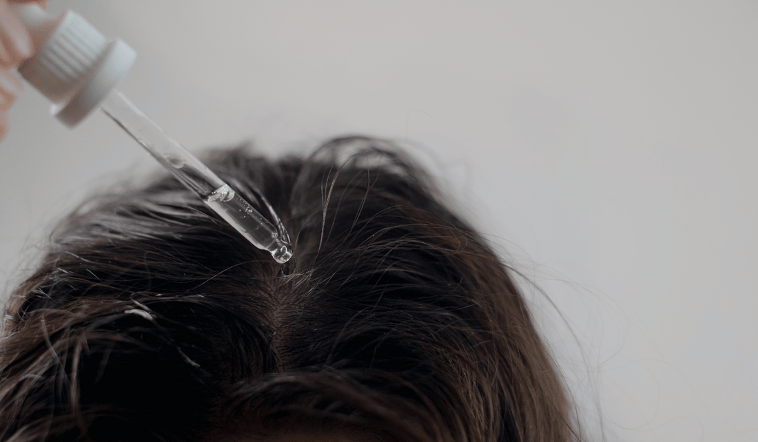 Dropper applying Organic Growth Oil to the scalp at the hairline to help stop hair fall