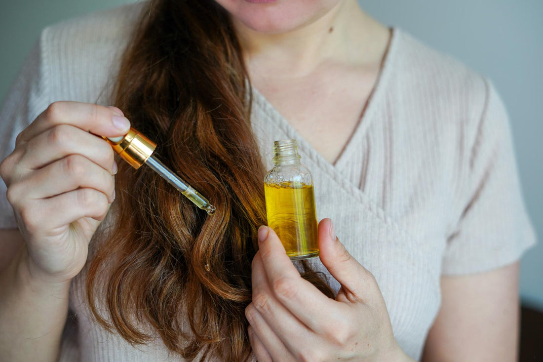 Woman applying Growth Oil with a dropper to her hair, holding the open bottle