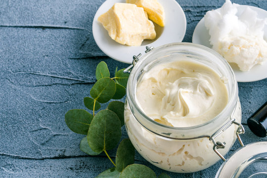 Open jar of whipped body butter beside shea and coconut butter chunks