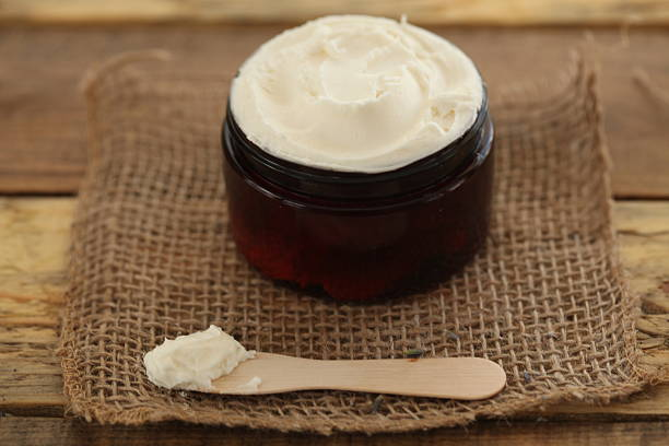 Jar of natural whipped butter moisturizer with a wooden spoon on burlap