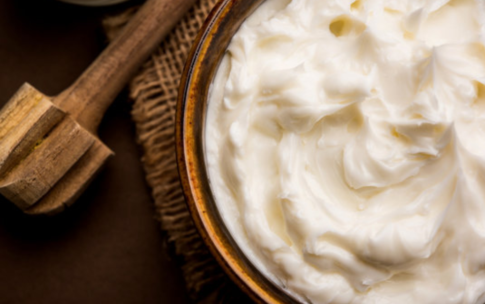 Bowl of whipped natural face moisturizer with a wooden spoon on burlap